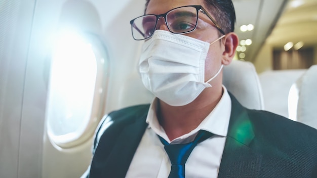 Viaggiatore che indossa una maschera facciale durante il viaggio in aereo commerciale.