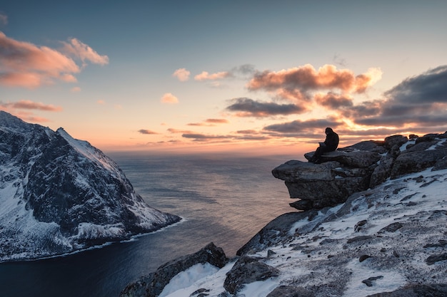 Viaggiatore che lavora a un computer portatile sulla montagna Ryten sul tramonto alle Isole Lofoten in Norvegia