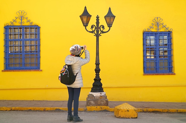 Viaggiatore che scatta foto di lampioni vintage con un edificio dai colori vivaci sullo sfondo