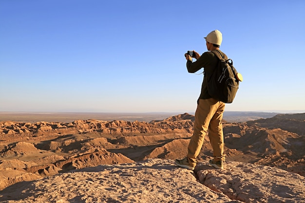 Viaggiatore che scatta foto sulla scogliera rocciosa di Valle de la Luna nel deserto di Atacama, Cile