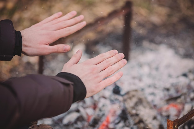 Viaggiatore che si scalda le mani vicino al fuoco all'aperto