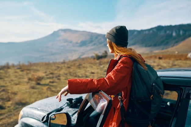 Viaggiatore con uno zaino vicino all'auto in montagna in estate e cielo blu aria fresca Foto di alta qualità