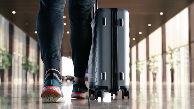 Viaggiatore con valigia che cammina con il trasporto di bagagli e passeggeri per tour nel terminal dell'aeroporto per i viaggi aerei