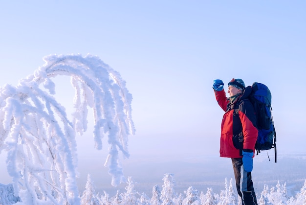 Viaggiatore con zaino e bastoncini per nordic walking in piedi in un gelido paesaggio invernale