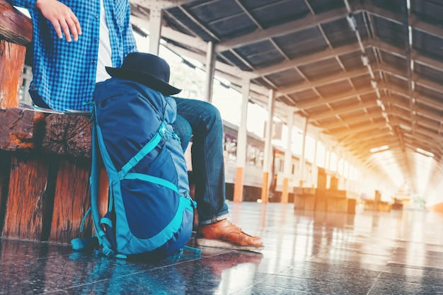 Viaggiatore con zaino e sacco a pelo turistico che utilizza la mappa per viaggiare alla stazione ferroviaria