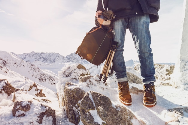 Viaggiatore del fotografo su una cima della montagna con attrezzature in mano