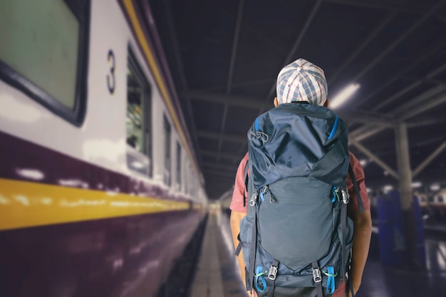 Viaggiatore del giovane con lo zaino nella ferrovia, concetto di viaggio.