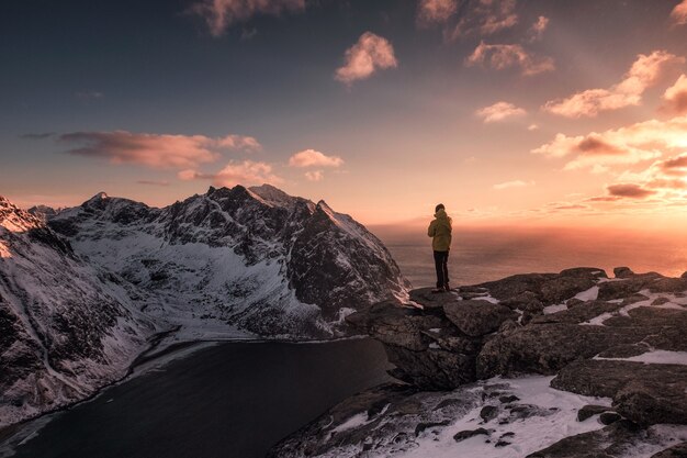 Viaggiatore dell'uomo in piedi sulla cima del monte Ryten nel tramonto in Norvegia