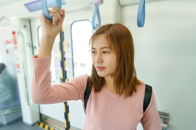 Viaggiatore della donna che tiene le rotaie del treno mentre prendendo sky train.