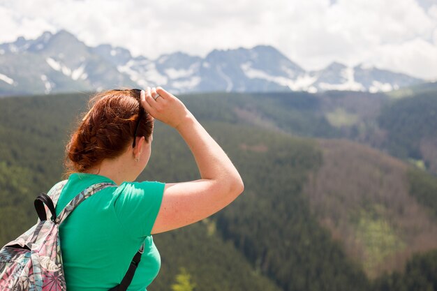 Viaggiatore della donna con lo zaino guardando incredibili montagne e foreste, concetto di viaggio wanderlust, spazio per il testo, momento epico atmosferico