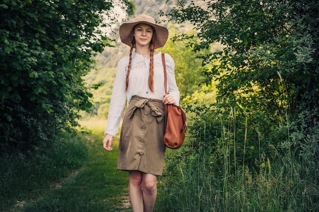 Viaggiatore della donna con zaino e cappello che cammina in montagne e foreste incredibili, concetto di viaggio wanderlust, spazio per testo, momento atmosferico. giorno della Terra