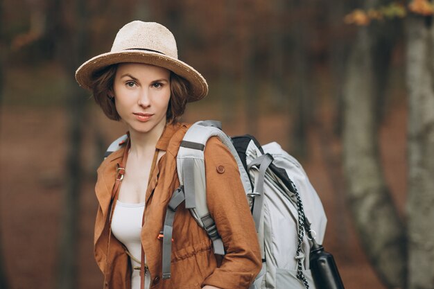 Viaggiatore della donna del ritratto con lo zaino che esamina foresta stupefacente