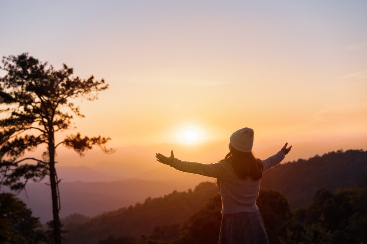 Viaggiatore della giovane donna che esamina alba sopra la montagna