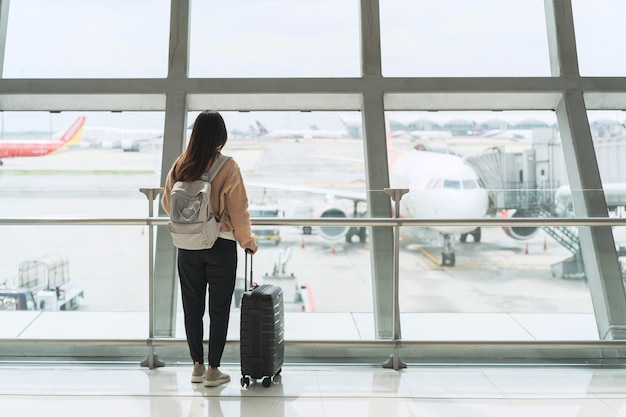 Viaggiatore della giovane donna che esamina l'aeroplano all'aeroporto, concetto di viaggio