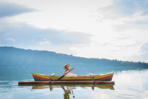 Viaggiatore della giovane donna che rema su una barca di legno a Pura Ulun Danu Bratan