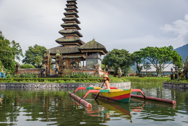 Viaggiatore della giovane donna che rema su una barca di legno a Pura Ulun Danu Bratan