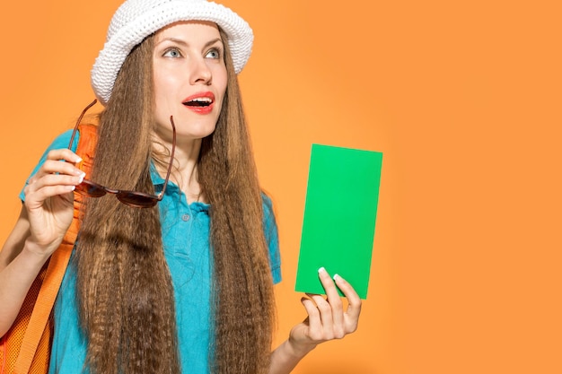 viaggiatore della giovane donna con lo zaino che indossa cappello e occhiali da sole in possesso di carta verde