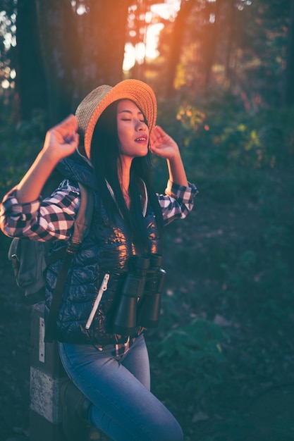 Viaggiatore della giovane donna con lo zaino in un bosco. Facendo un&#39;escursione ad estate.