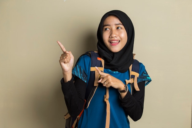 Viaggiatore della giovane donna musulmana asiatica che indossa il hijab sorridente fiducioso che indica con le dita in direzioni diverse.