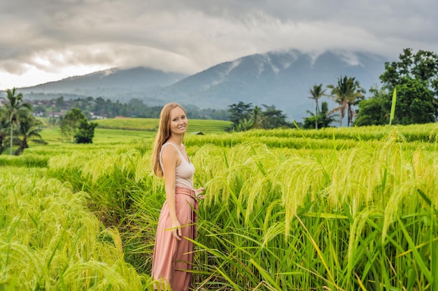 Viaggiatore della giovane donna sulle belle terrazze di riso di Jatiluwih sullo sfondo dei famosi vulcani di Bali, Indonesia
