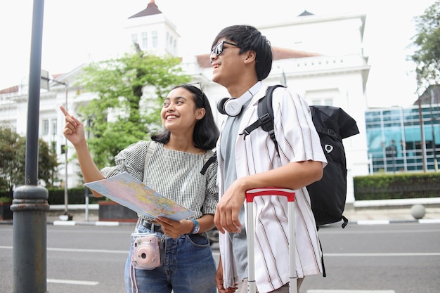 Viaggiatore di coppia asiatica in stile casual che viaggia per la città ragazza che dà indicazioni al fidanzato