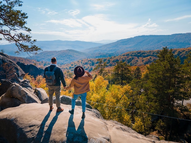 Viaggiatore di coppia seduto sulla cima della roccia con uno splendido paesaggio di foresta autunnale