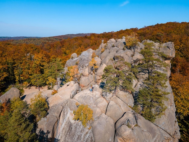 Viaggiatore di coppia seduto sulla cima della roccia con uno splendido paesaggio di foresta autunnale