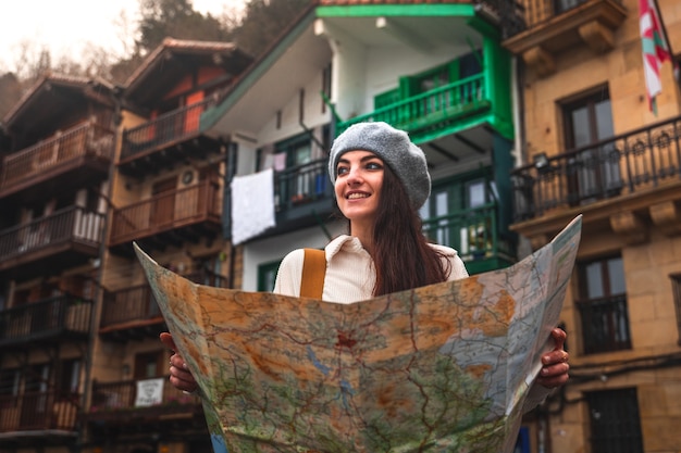 Viaggiatore di giovane donna caucasica alla ricerca di una mappa e facciate colorate dietro