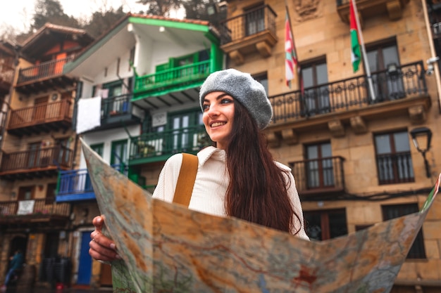 Viaggiatore di giovane donna caucasica alla ricerca di una mappa e facciate colorate dietro