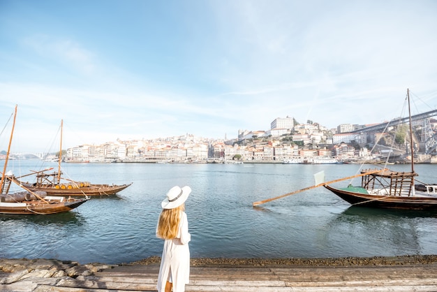 Viaggiatore di giovane donna che gode di una splendida vista sul paesaggio urbano del fiume Douro e delle tradizionali barche portoghesi durante la luce del mattino a Porto, Portugal