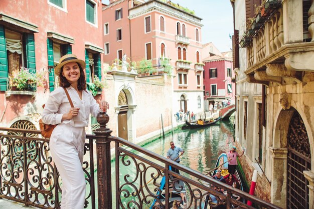 Viaggiatore di giovane donna graziosa in piedi al canale trasversale del ponte di Venezia