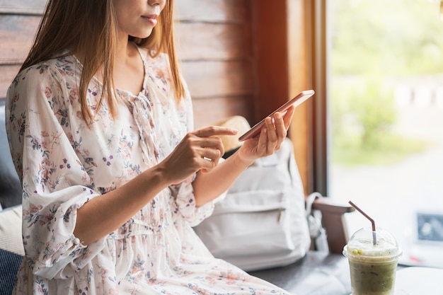 Viaggiatore di giovane donna utilizzando smart phone nella caffetteria durante il viaggio