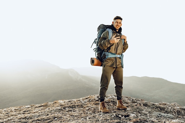 Viaggiatore di giovane uomo caucasico con grande zaino escursionismo in montagna