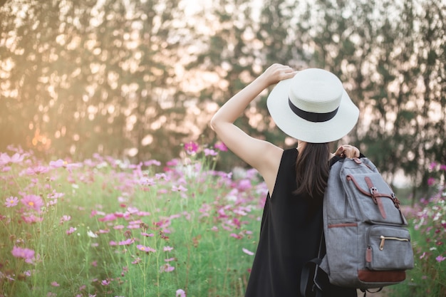 viaggiatore donna con zaino e guardando stupendi campi di fiori belli