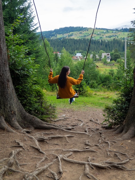 Viaggiatore donna godendo di oscillare su altalena e vista sulle montagne