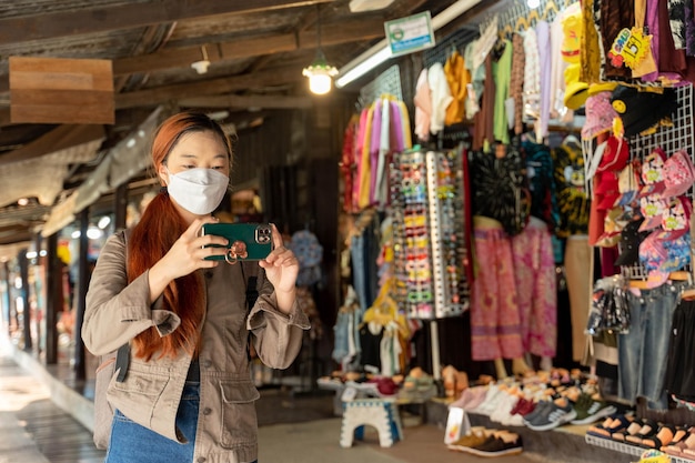 Viaggiatore donna hipster con maschera e zaino che scatta foto con il cellulare in ayothaya thailandia Concetto di relax per le vacanze di viaggio