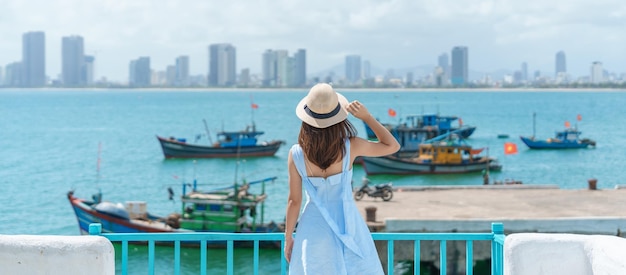 Viaggiatore donna in visita al porto turistico di Son tra Turista con abito blu e cappello che viaggia nella città di da Nang Concetto di viaggio in Vietnam e nel sud-est asiatico