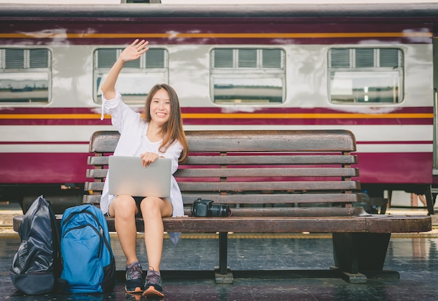 viaggiatore donna seduta da solo e ridendo con laptop e borsa