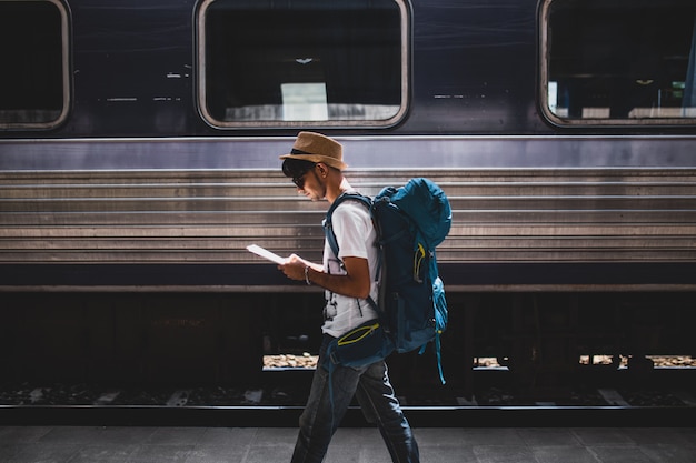 Viaggiatore è zaino in spalla e cammina da solo alla stazione ferroviaria.