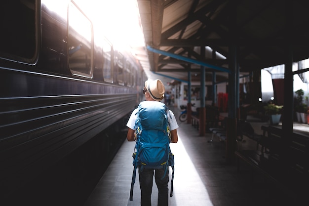 Viaggiatore è zaino in spalla e cammina da solo alla stazione ferroviaria.