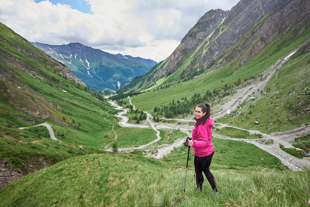 Viaggiatore femminile allegro che fa un'escursione nelle montagne