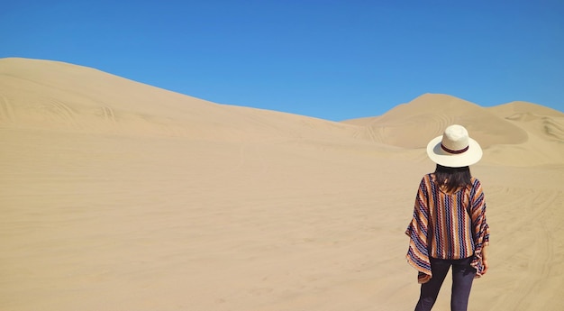 Viaggiatore femminile che guarda le bellissime dune di sabbia del deserto di Huacachina nella regione di Ica Perù