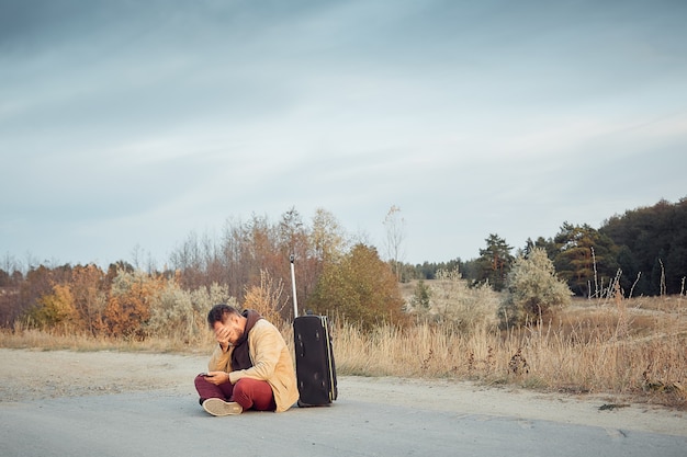 Viaggiatore frustrato si perde e non riesce a ricevere il segnale del telefono, uomo solo con una valigia