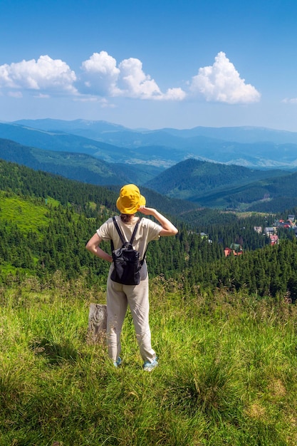 Viaggiatore in cappello e zaino che riposa nella natura Una ragazza turistica guarda il panorama delle montagne