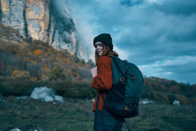 Viaggiatore in un maglione con uno zaino sulla schiena turismo nuvole cielo paesaggio Foto di alta qualità