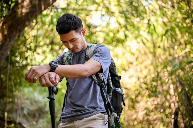 Viaggiatore maschio asiatico stanco ed esausto con attrezzatura da trekking che fa escursioni nella montagna rocciosa