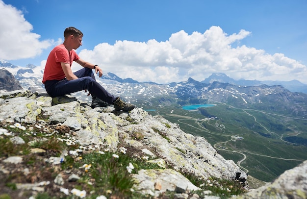 Viaggiatore maschio seduto in cima a una montagna rocciosa