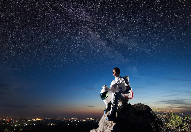 Viaggiatore spaziale seduto su una montagna rocciosa sotto il cielo blu