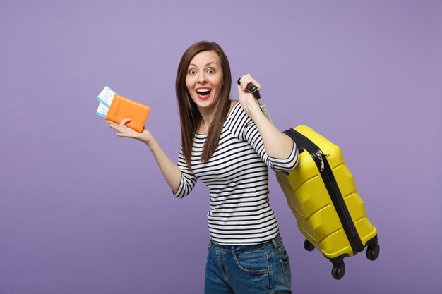 Viaggiatore turista donna ragazza in abiti casual a righe in posa isolata su sfondo viola viola ritratto in studio. Passeggero che viaggia all'estero per viaggiare nei fine settimana. Concetto di viaggio in volo aereo.