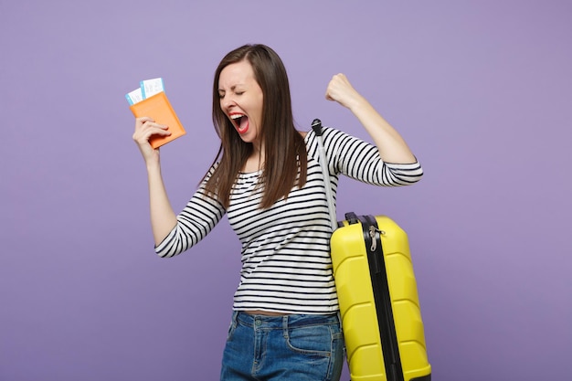 Viaggiatore turista donna ragazza in abiti casual a righe in posa isolata su sfondo viola viola ritratto in studio. Passeggero che viaggia all'estero per viaggiare nei fine settimana. Concetto di viaggio in volo aereo.